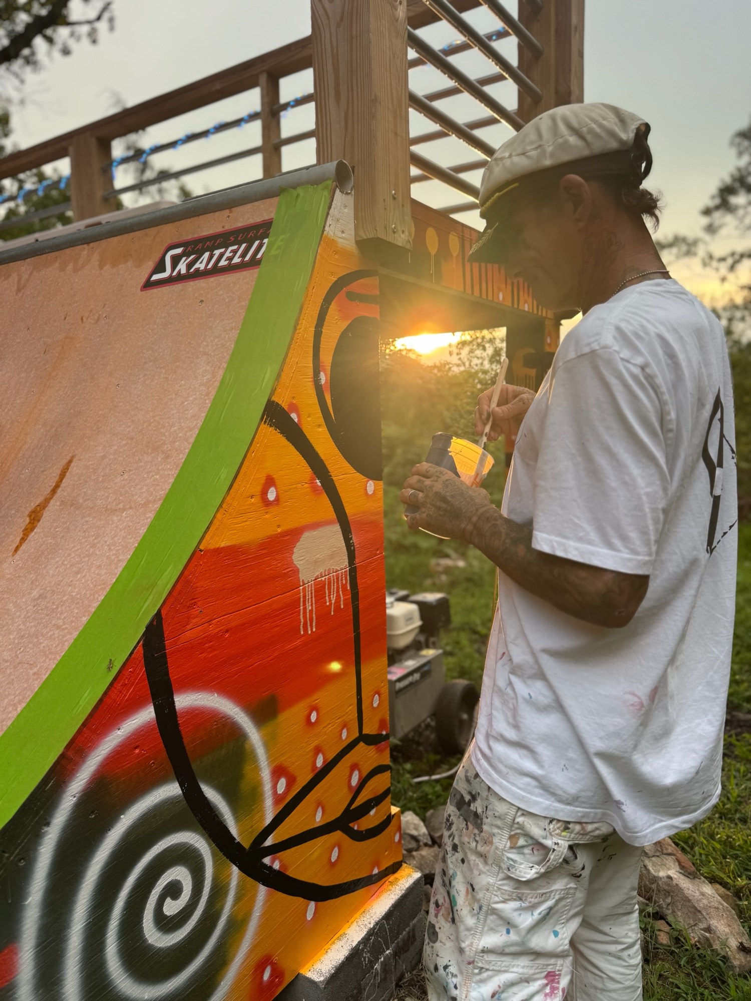 Kris mixing paint beside the ramp as the sun drops