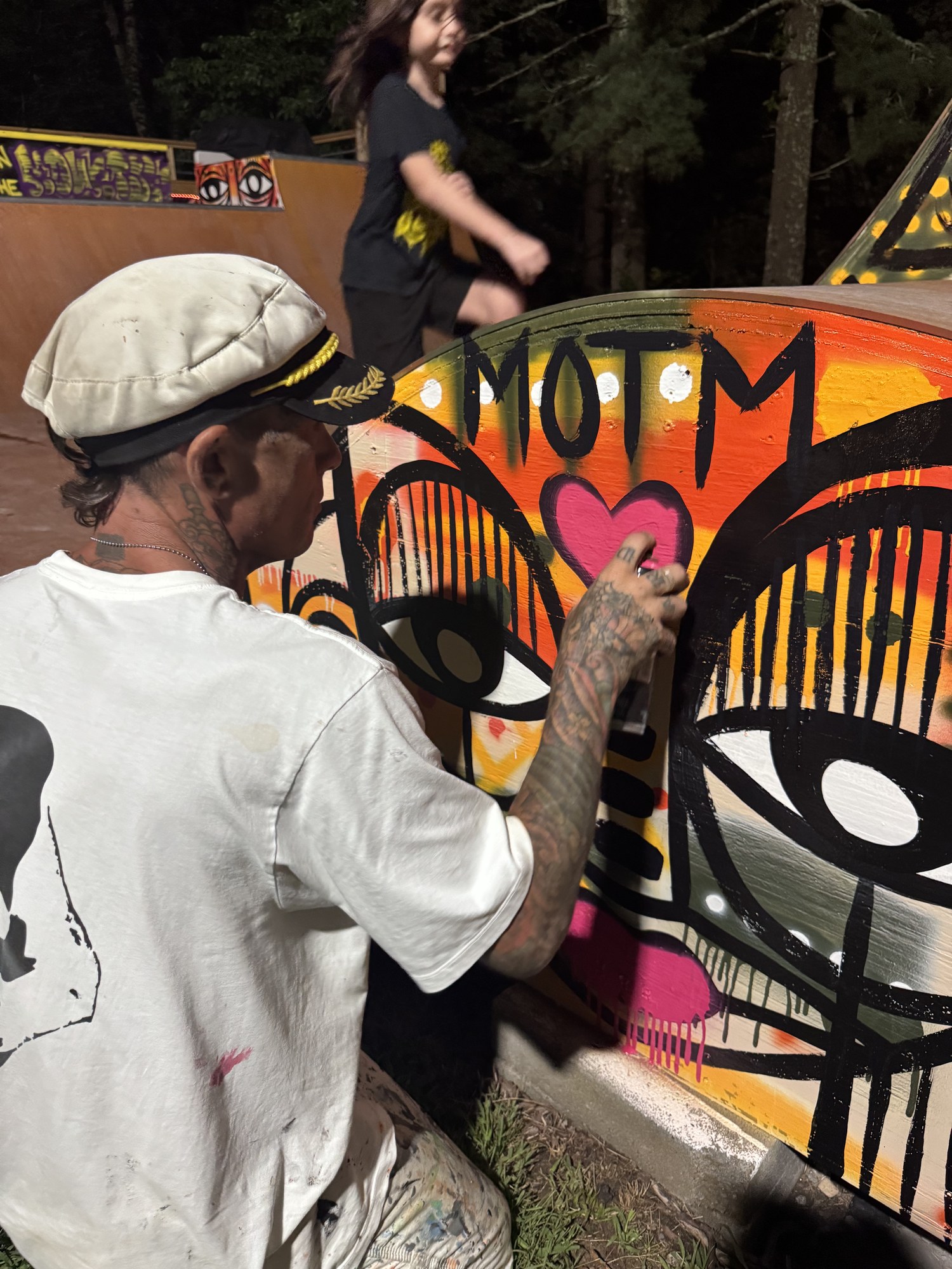 Kris spray-painting MOTM and a pink heart on the ramp wall