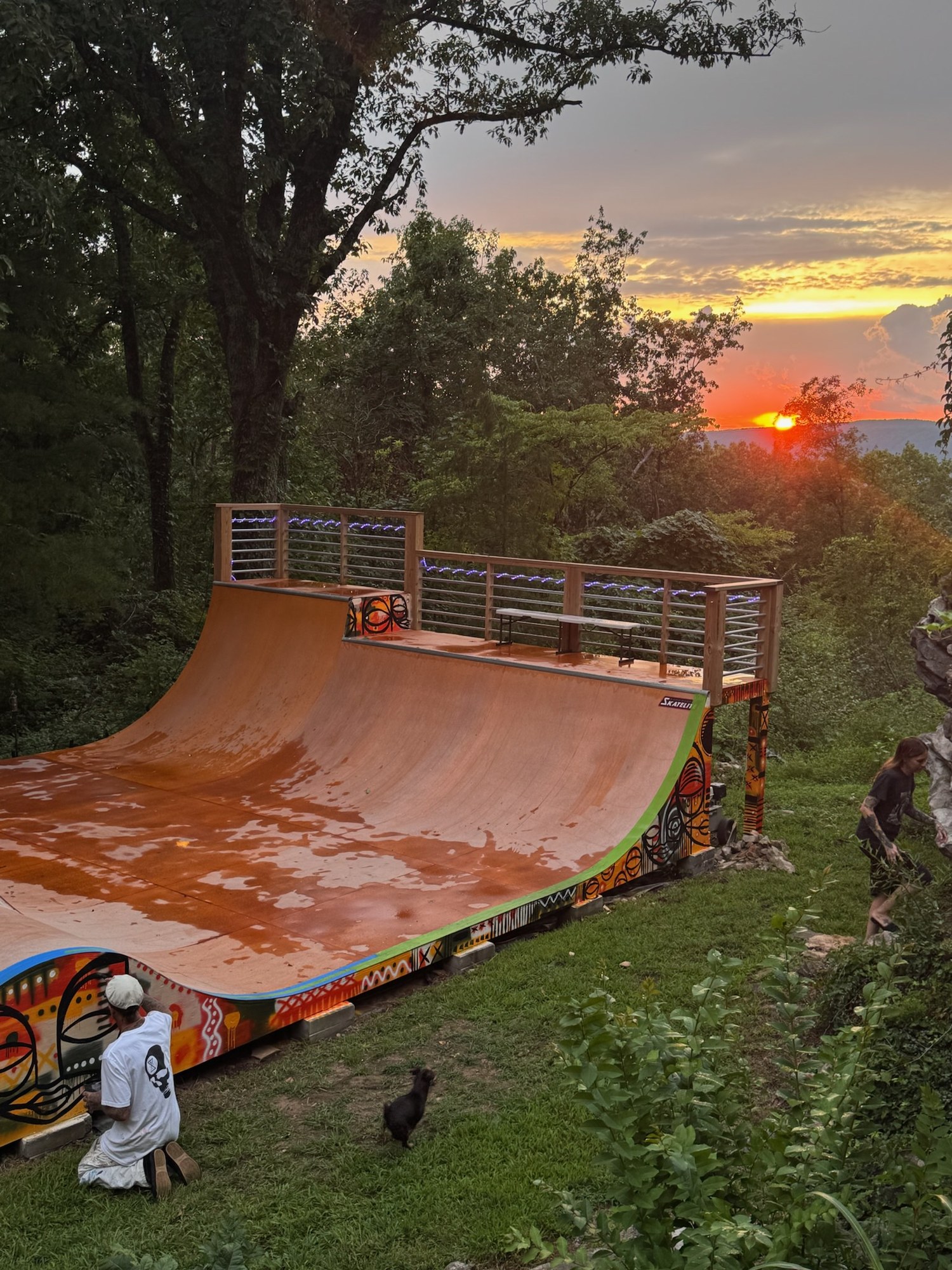 The backyard mini ramp at sunset, Kris painting the mural on the side